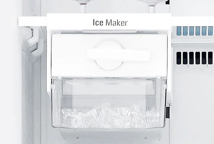 냉장고 내부의 얼음 제조기가 보입니다. 얼음 제조기에는 Ice Maker라는 텍스트가 적혀 있으며, 투명한 용기 안에 얼음이 담겨 있습니다. 주변은 흰색의 깔끔한 디자인으로 되어 있습니다.